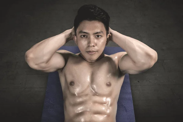 Sweaty young man doing crunches exercises