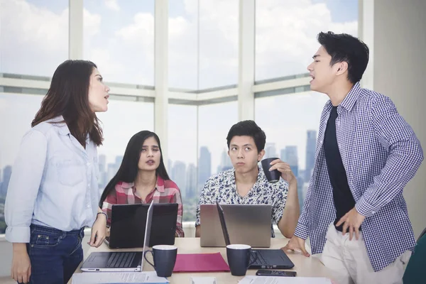 Zwei junge Arbeiter streiten sich bei Treffen im Büro — Stockfoto