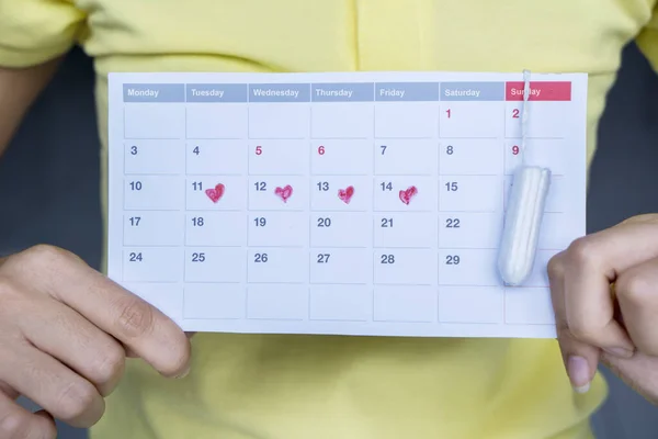 Неизвестная женщина показывает календарь с тампоном — стоковое фото