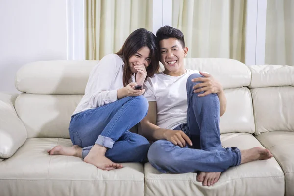 Молодая счастливая пара смотрит телевизор дома — стоковое фото