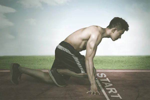 年轻的肌肉男子跪在起跑线上 — 图库照片