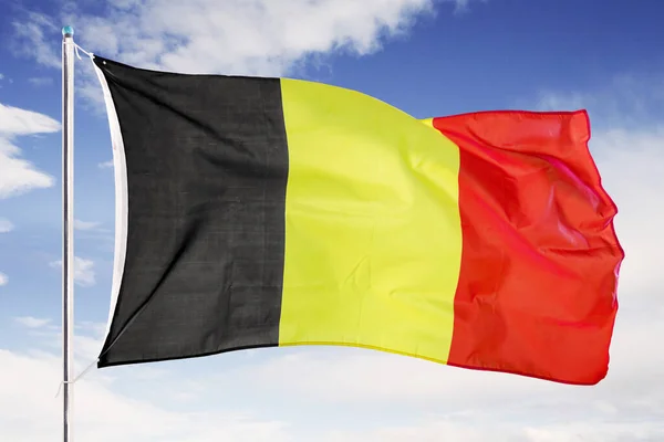 België nationale vlag onder blauwe lucht — Stockfoto