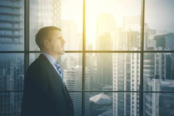 Kaukasische zakenman kijkt pensive in de buurt venster — Stockfoto