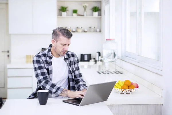 Běloch pracující s laptopem v kuchyni — Stock fotografie