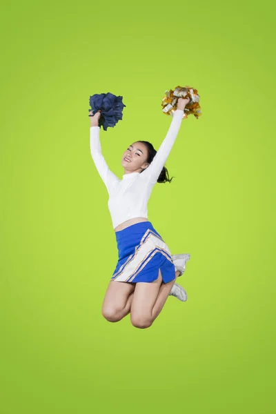 Cheerleader meisje springen met pom poms op studio — Stockfoto