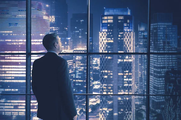Masculino gerente olhando para noite cidade no o escritório — Fotografia de Stock