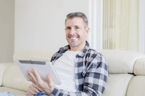 Usmívající se běloch pomocí tabletu na gauči — Stock fotografie