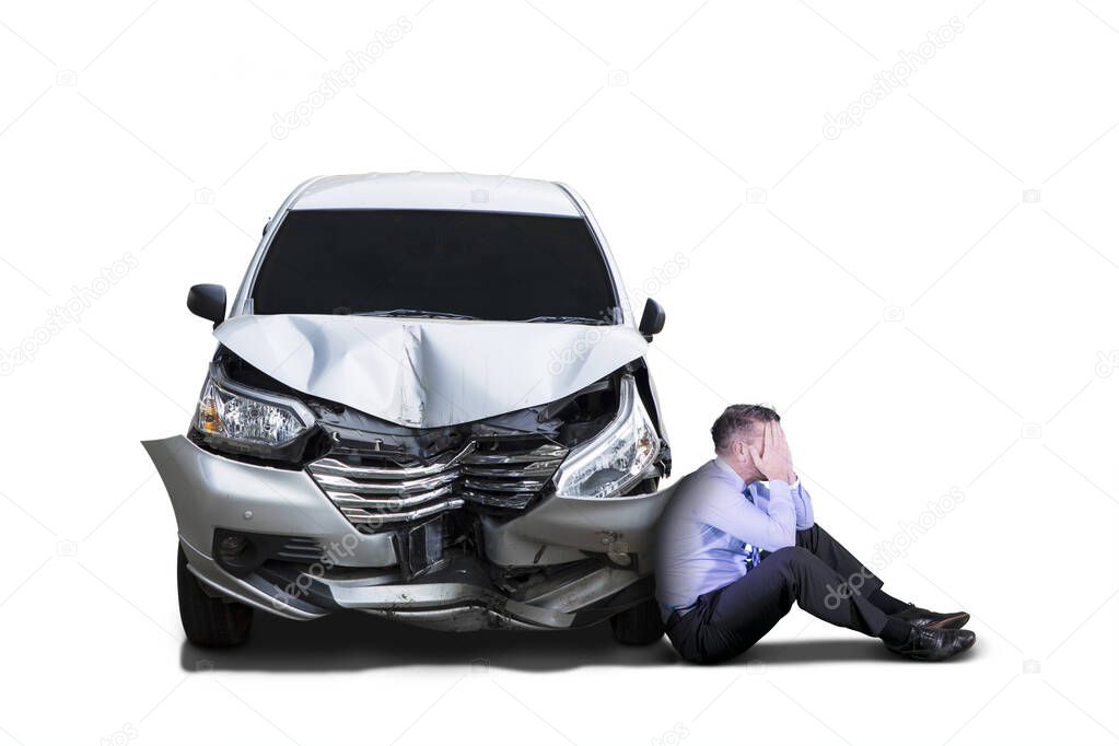 Businessman looks depressed near damaged car