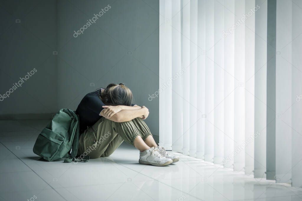 Teenage girl crying near the window