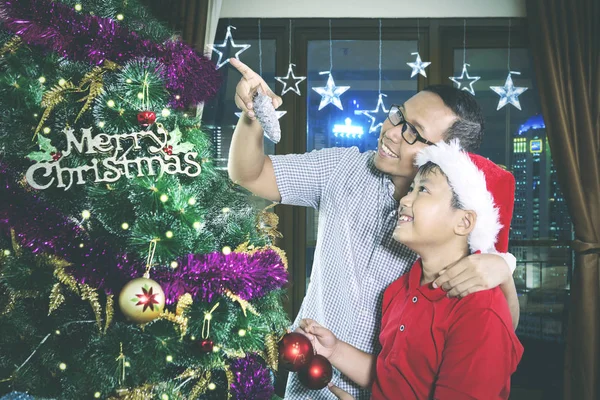 Asiático padre y su hijo mirando un árbol de Navidad —  Fotos de Stock