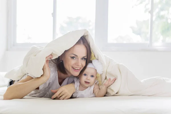 Beautiful woman and her baby under a blanket — 图库照片