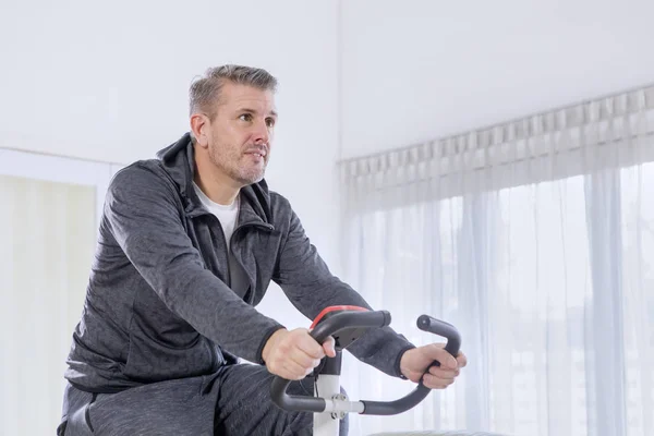 Caucasian man exercising on a spin bike at home