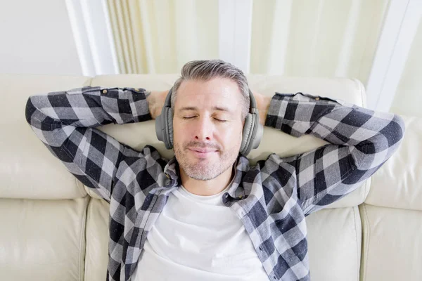 Homem caucasiano ouve música durante o relaxamento no sofá — Fotografia de Stock