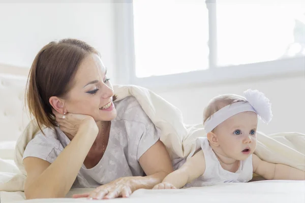 Caucasian woman having fun with her baby on bed — Stock Photo, Image