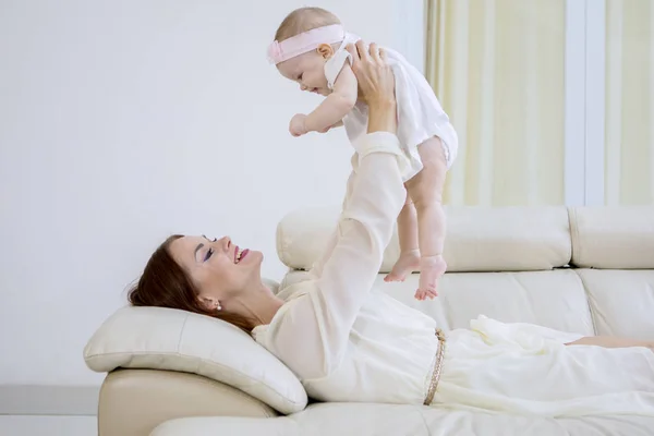 Kaukasische Frau spielt mit ihrem Baby auf Couch — Stockfoto