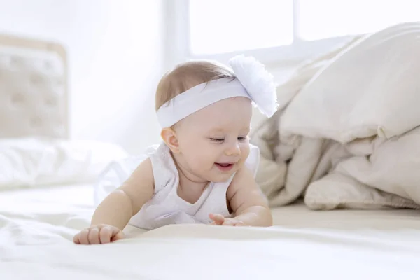 Cute baby girl wearing white dress on the bed — Stock Photo, Image