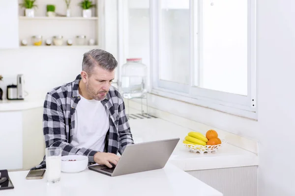 Freelancer working with a laptop during breakfast — Stock fotografie