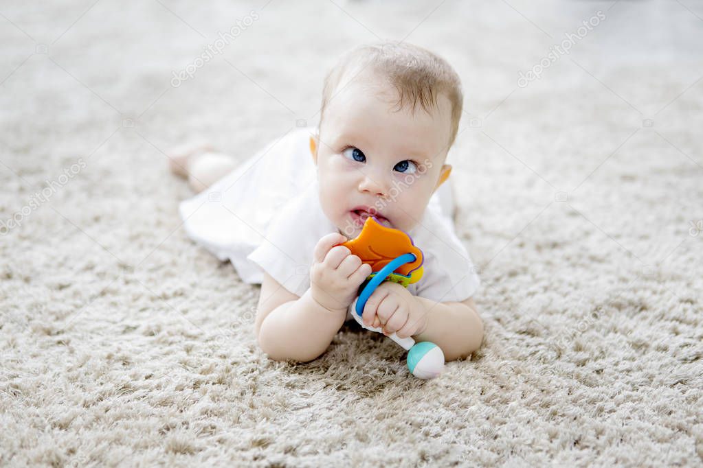 Cute baby girl playing with toys on the fur carpet