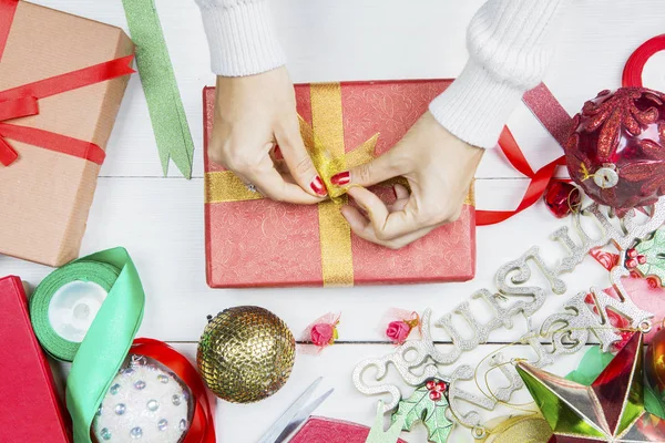 Bilinmeyen bir kadının elleri Noel hediyesini süslüyor. — Stok fotoğraf