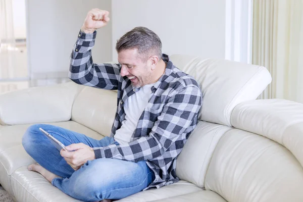 Schöner Mann, der sich glücklich ausdrückt, während er Tablet benutzt — Stockfoto