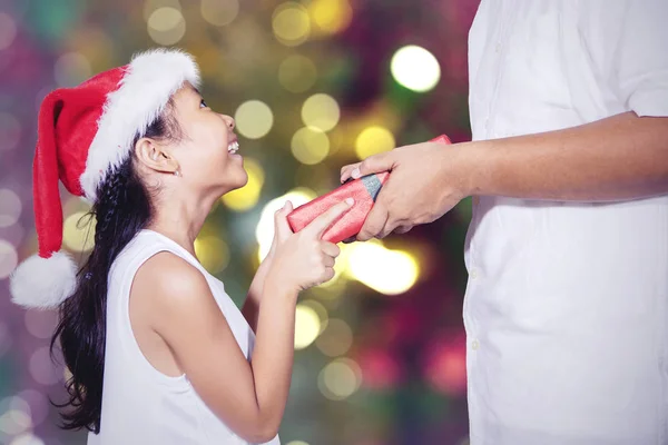 Happy little girl gets a Christmas gift from her father — Stock Photo, Image