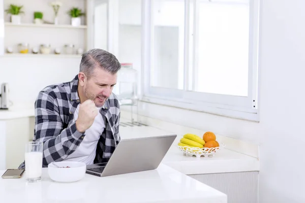 Happy man using a laptop during breakfast — Stock fotografie