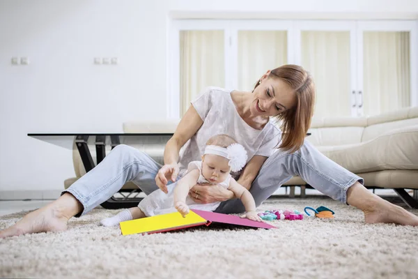 Szczęśliwa matka i jej dziewczynka bawią się na dywanie — Zdjęcie stockowe