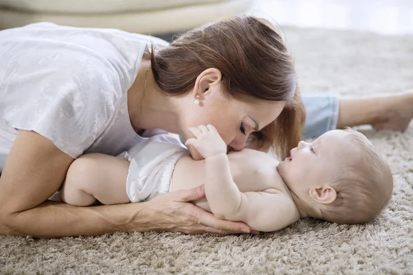 Glückliche Mutter küsst Bauch ihres kleinen Mädchens zu Hause — Stockfoto