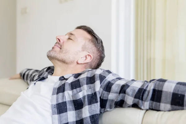 Homem relaxante no sofá com os olhos fechados — Fotografia de Stock