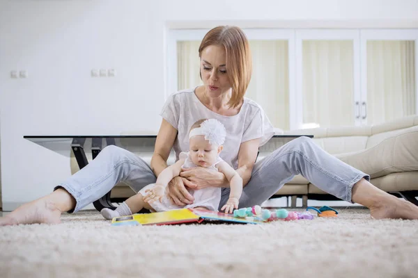 母親と赤ん坊の女の子はカーペットの上で一緒に遊ぶ — ストック写真