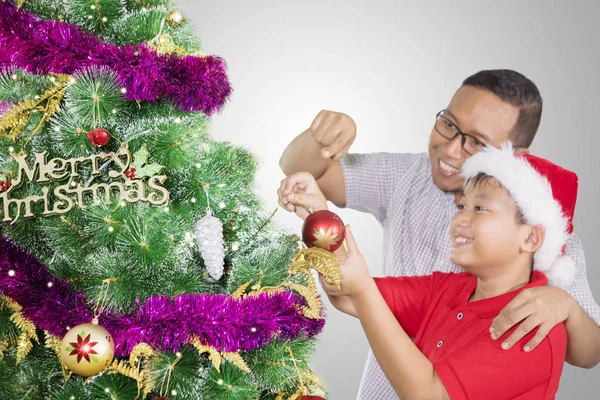 Frühchen vom Vater beim Schmücken einer Tanne unterstützt — Stockfoto