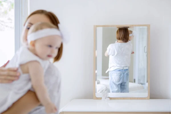 Vista posteriore di una madre che tiene il suo bambino nello specchio — Foto Stock