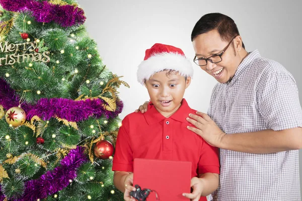 Sorprendidos padre e hijo abriendo un regalo de Navidad —  Fotos de Stock