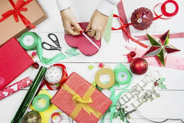 As mãos de mulher decoram um presente de Natal com fita — Fotografia de Stock