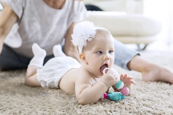 Adorabile bambina che gioca con i giocattoli sul tappeto — Foto Stock