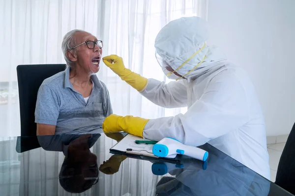 在医院里 穿着危险物品的医生正在对老年男子进行擦拭试验 以采集大肠病毒爆发样本 — 图库照片