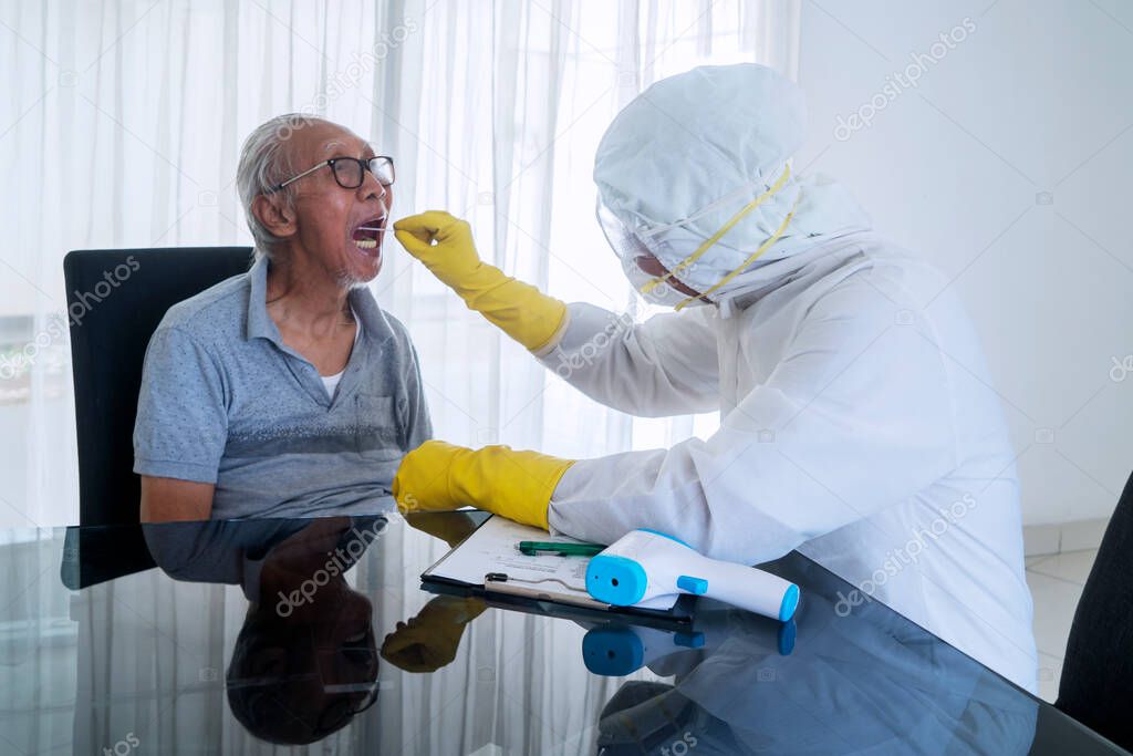 Doctor in hazmat suit doing swab test on elderly man to take coronavirus outbreak sample in the hospital