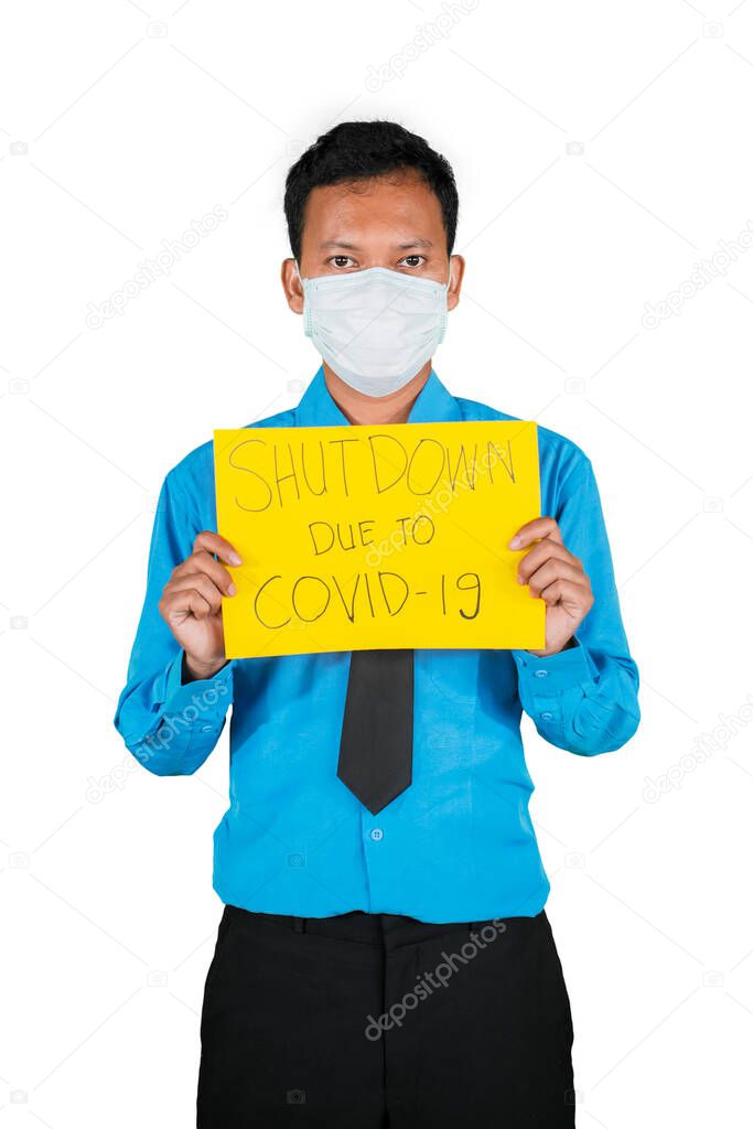 Businessman wearing a medical mask showing text of Shutdown Due to Covid-19 in the studio, isolated on white background