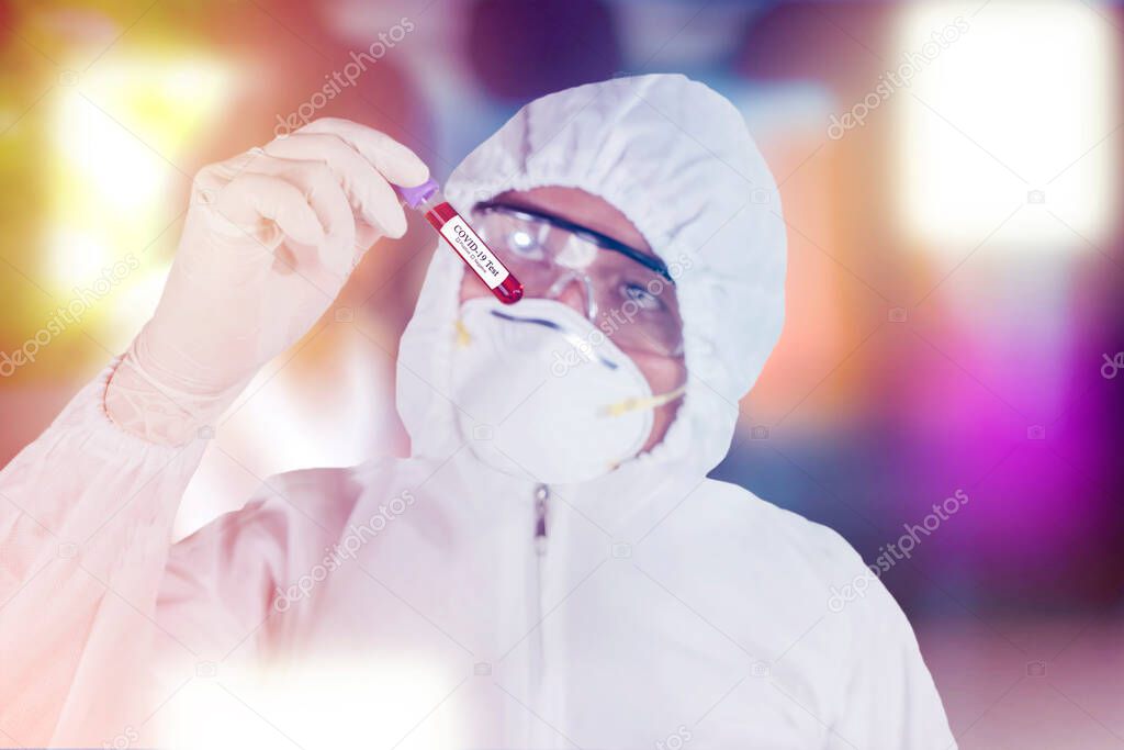 Medical worker in hazmat suit holding test tube with blood for analysis and sampling of Coronavirus
