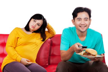 Kızgın hamile kadın, çünkü kocası onu görmezden geldi. Kanepede oturup stüdyoda televizyon izlerken.