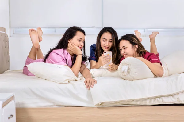 Grupo Adolescentes Usando Celular Deitado Cama Enquanto Confiam Juntos Quarto — Fotografia de Stock
