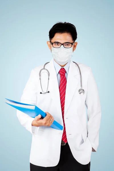Jovem Médico Vestindo Uma Máscara Enquanto Segura Documento Está Estúdio — Fotografia de Stock
