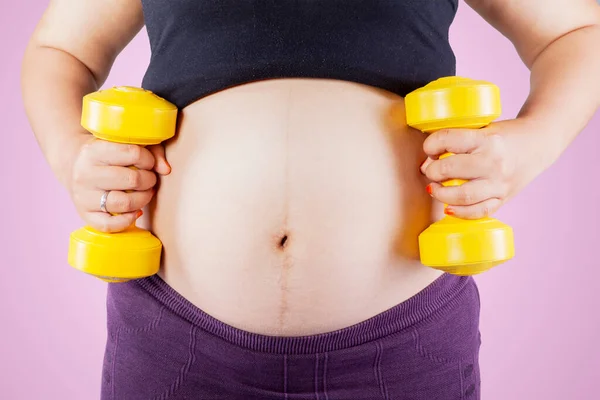 Großaufnahme Von Schwangerschaftsbauch Trainiert Mit Zwei Kurzhanteln Und Steht Studio — Stockfoto