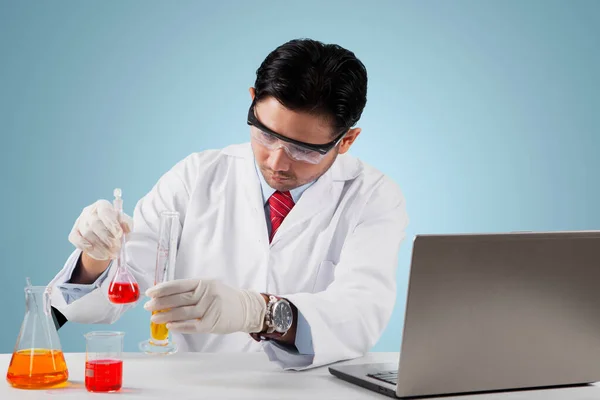 在实验室生产Covid 19疫苗的过程中 男性科学家正在混合化学液体 — 图库照片