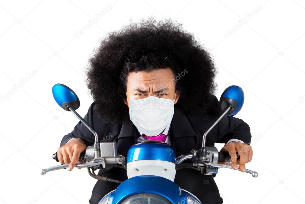 Afro businessman wearing a face mask and riding a motorcycle in the studio. Isolated on white background