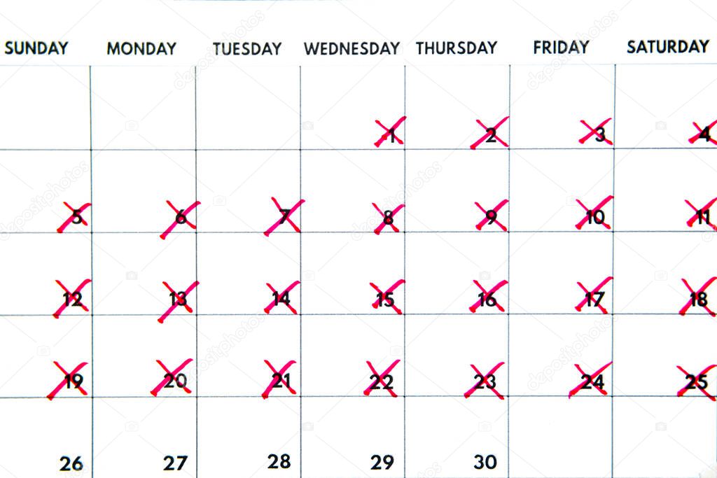Close up of a calendar showing days being crossed off with a red marker for reminder