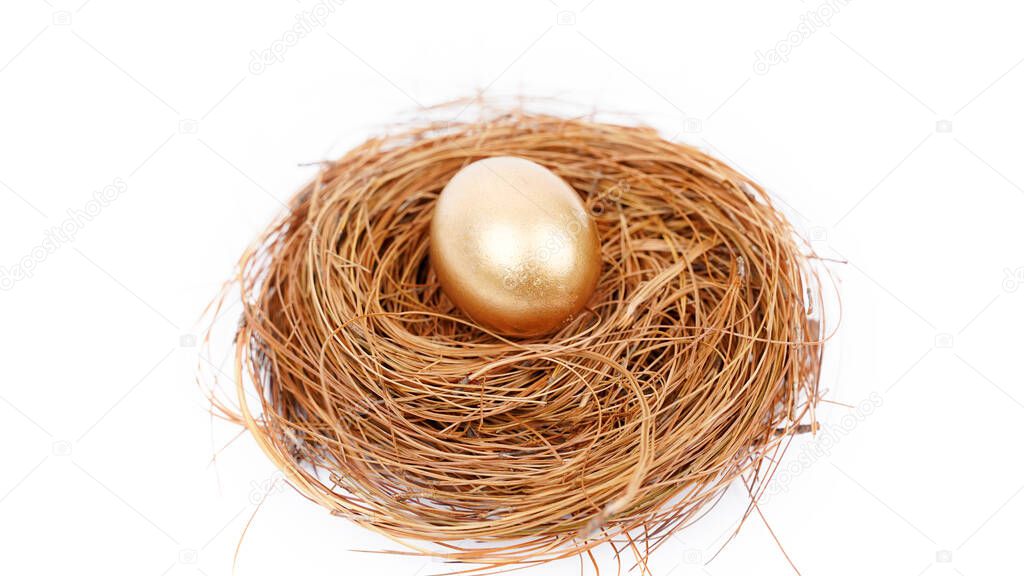 Close up of a golden egg on the straw nest. Isolated on white background