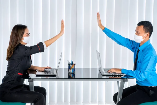 Two business people wearing a mask and giving high five hands with contactless while working in the office at new normal lifestyle