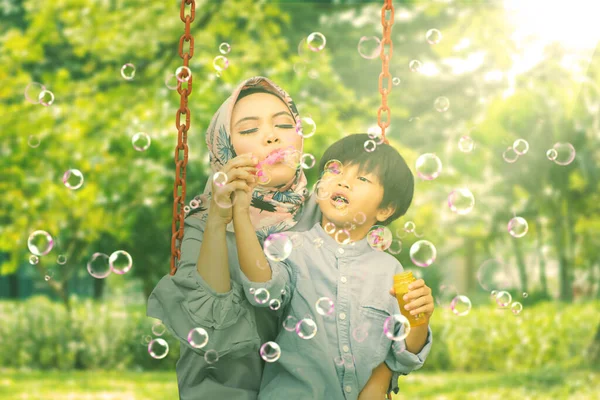 Küçük Çocuk Annesiyle Parkta Salıncakta Sabun Köpüğü Oynuyor — Stok fotoğraf