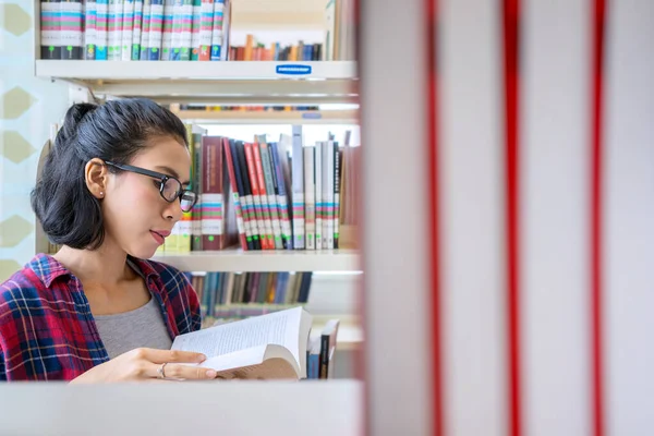 女大学生站在书架上看书 在图书馆开枪射击 — 图库照片